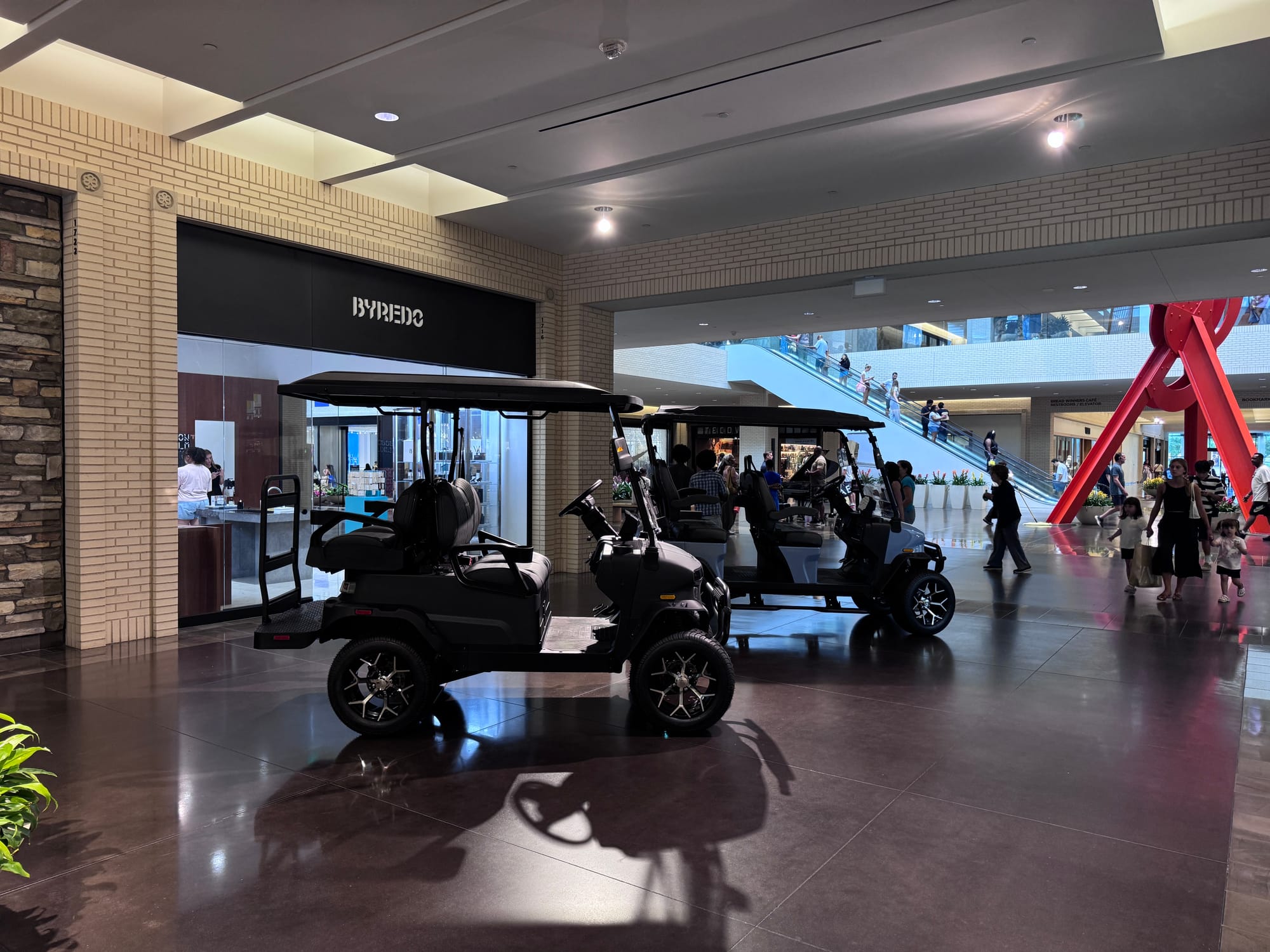 A Denago Matte Black Nomad XL and Glacier Rover XL at NorthPark Center, with Mark di Suvero's sculpture Ad Astra behind them