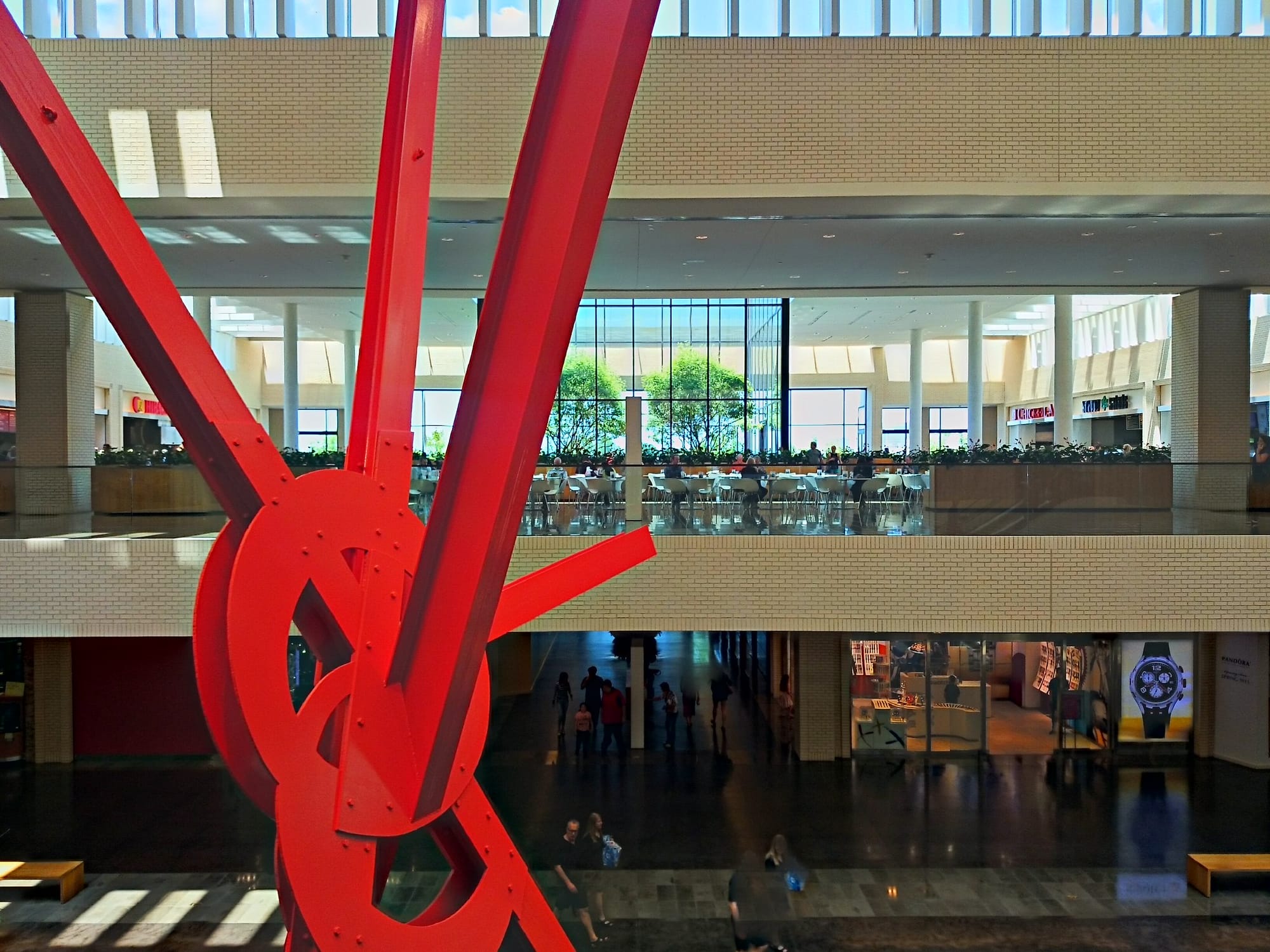 Mark di Suvero's sculpture Ad Astra, red painted steel I-beams and bolted plates, rising through the two-story NorthCourt at NorthPark Center in Dallas.