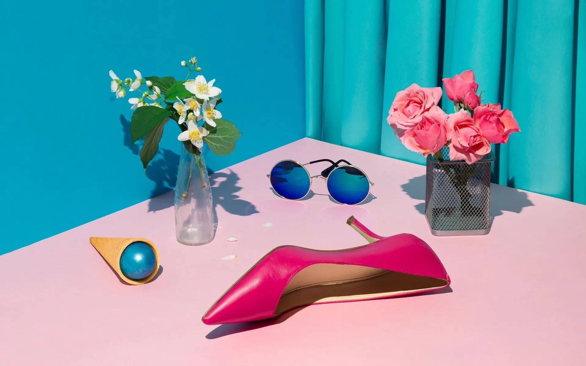 A shoe, ice cream, sunglasses, and flowers on a table