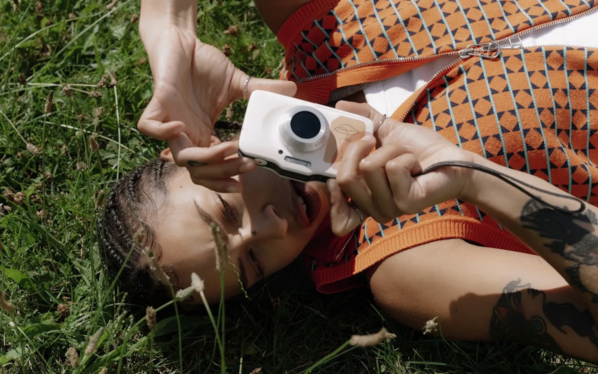 Woman using a disposable camera and laying down on the grass