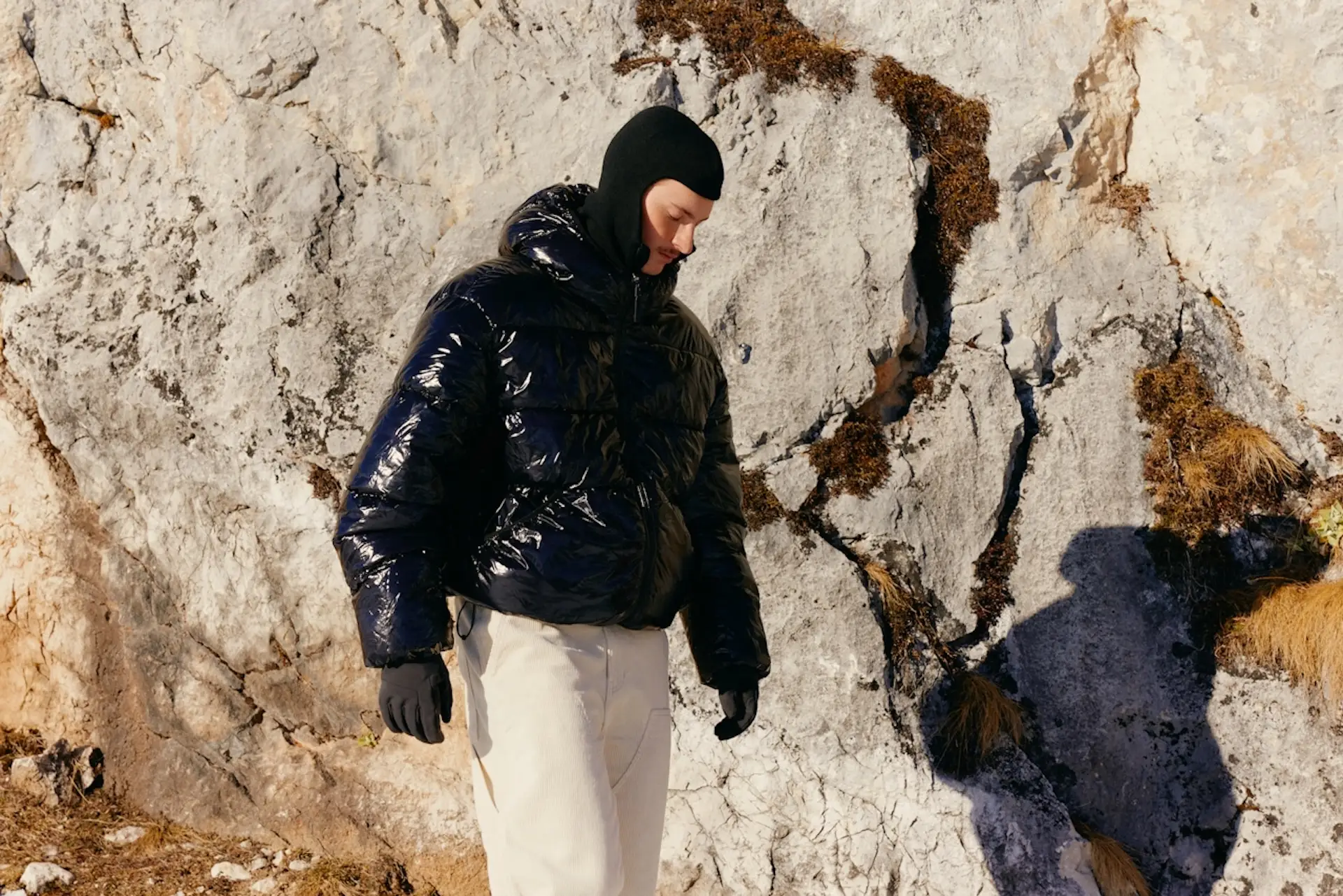Man in a coat walking by a cliff face