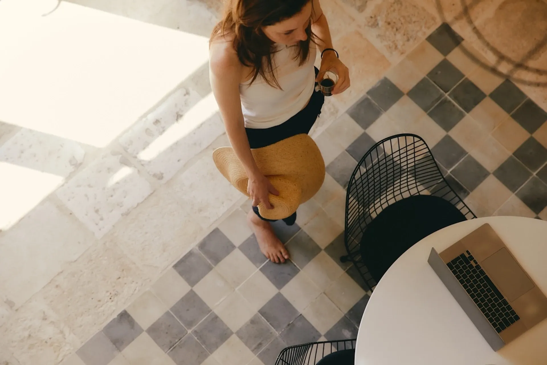 A woman taking her drink to sit by her laptop