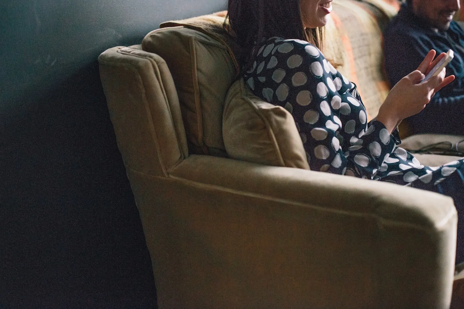 A woman using her mobile phone while sitting on a couch