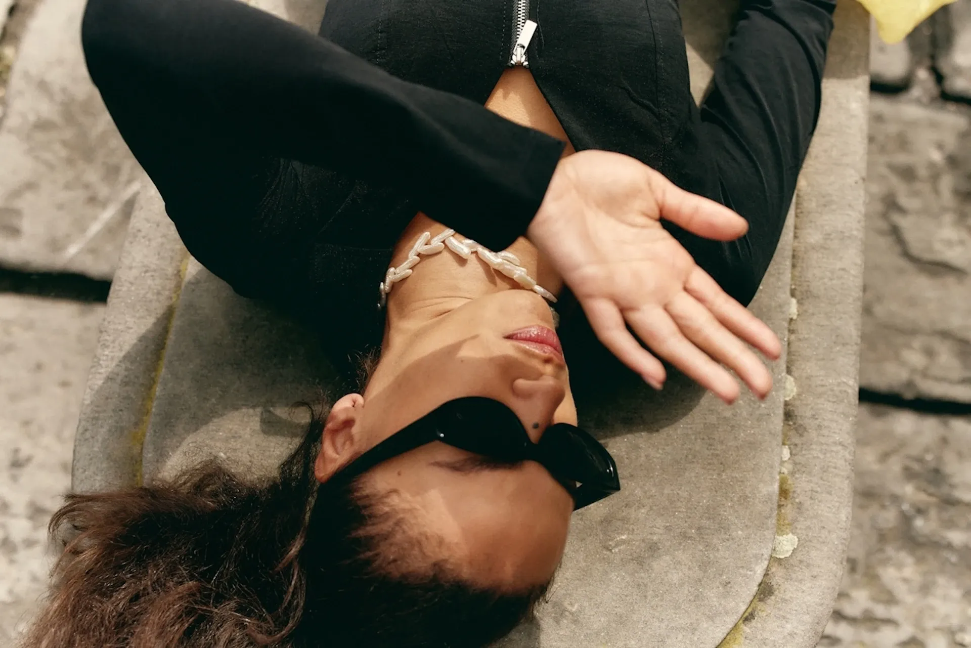 A person in sunglasses shielding their face from the sun