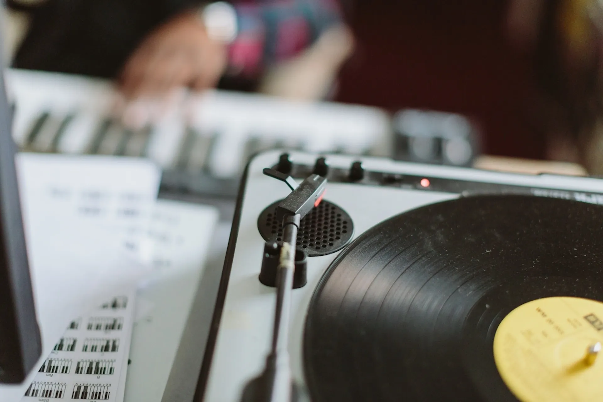 Someone playing keyboards with a vinyl record in the foreground