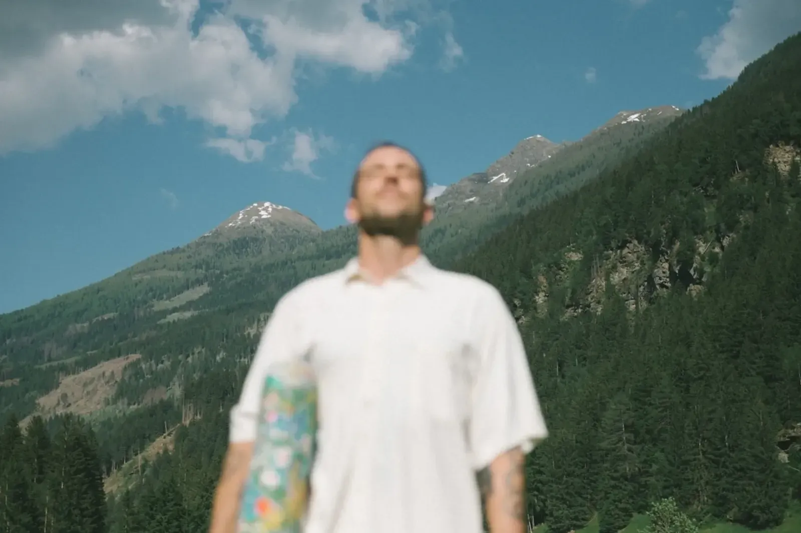 A man standing in front of a mountain on a sunny day