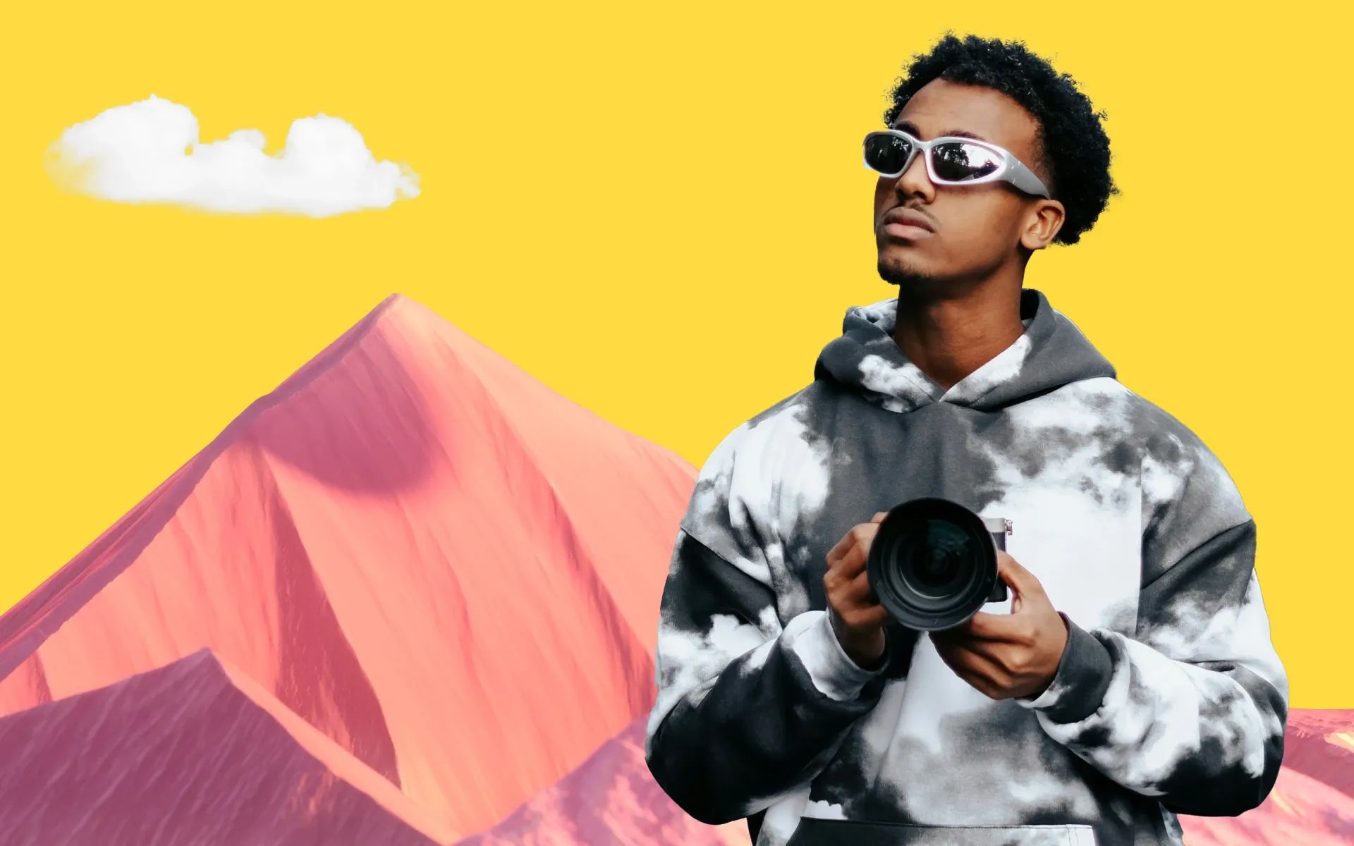 A man holding a camera and standing in front of a mountain