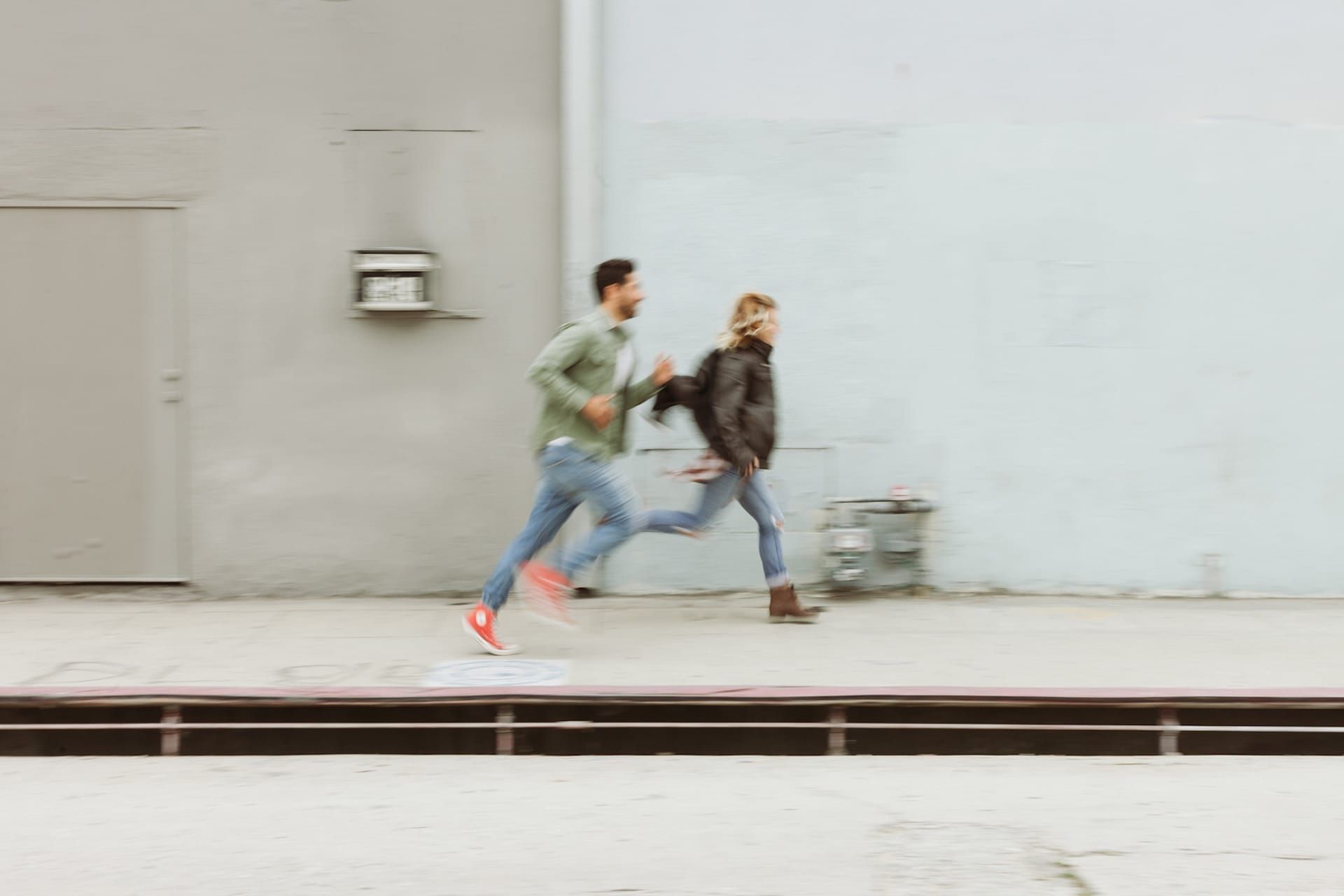 Two people running across an old train platform