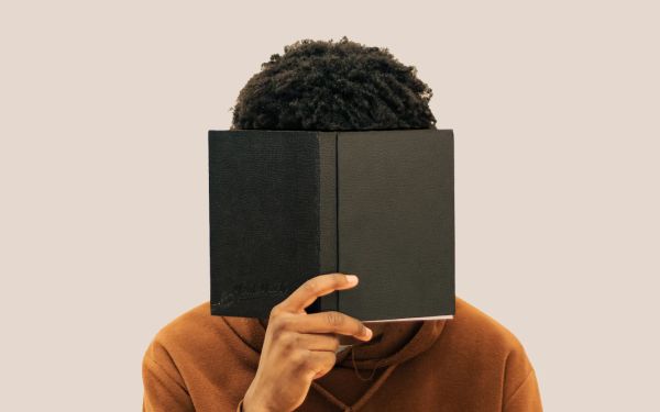 Person hiding their face behind a book