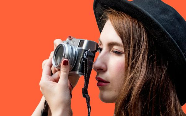 Woman in a hat taking a photo with a camera