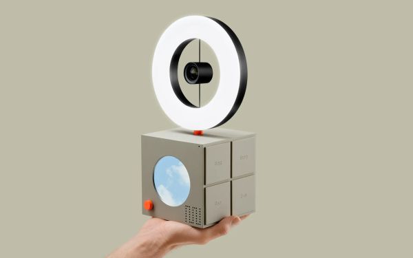 Hand holding a cube with a ring light on top of it