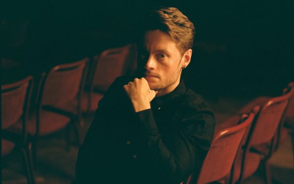 A photo of Christoffer Moe Ditlevsen, sitting on a red chair. Photo by Sune Chee.