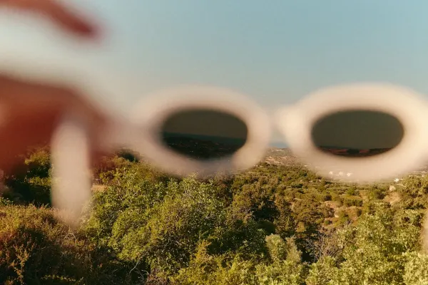 Out-of-focus sunglasses held above a field