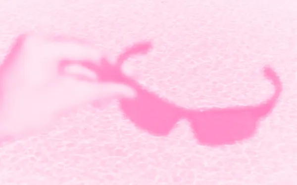 Someone holding a pair of sunglasses in front of a pool