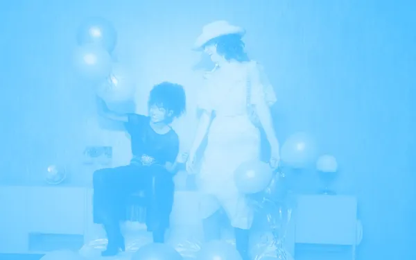 Two friends playing with balloons and laughing. One of them is wearing a cowboy hat