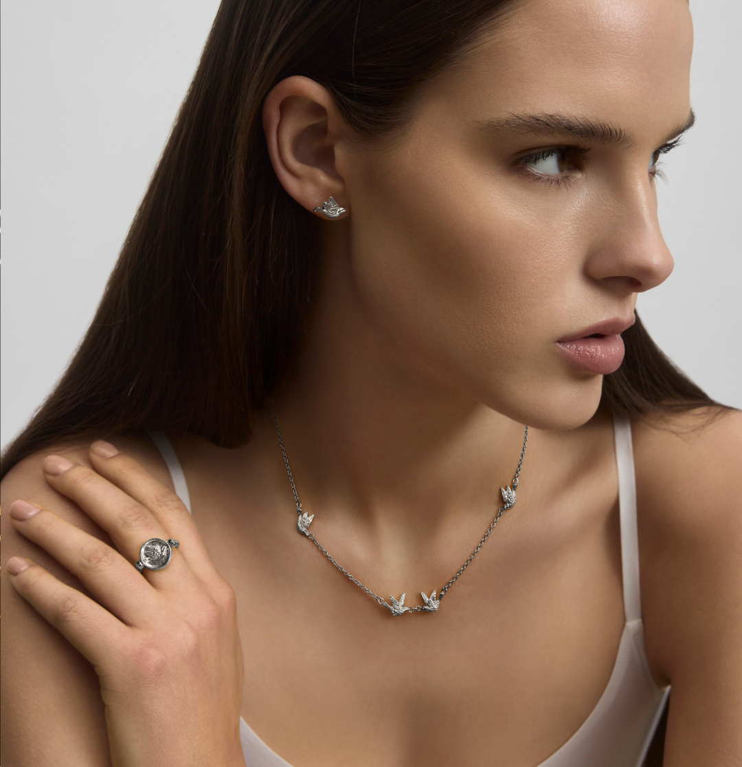 Model wearing the Mini Dove Necklace in pure platinum with Dove Stud Earrings and Dove Flip Ring from the Menē 2026 Mother’s Day Collection.