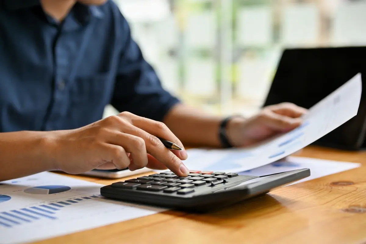 Business owner and analyst planning chatbot ROI with charts and a calculator