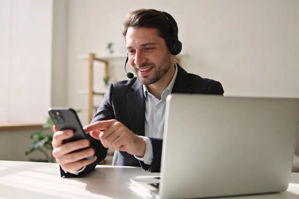 A customer moving between mobile and desktop support in a bright home workspace