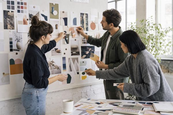 Marketing agency team arranging campaign proofs and colour swatches on a studio planning wall