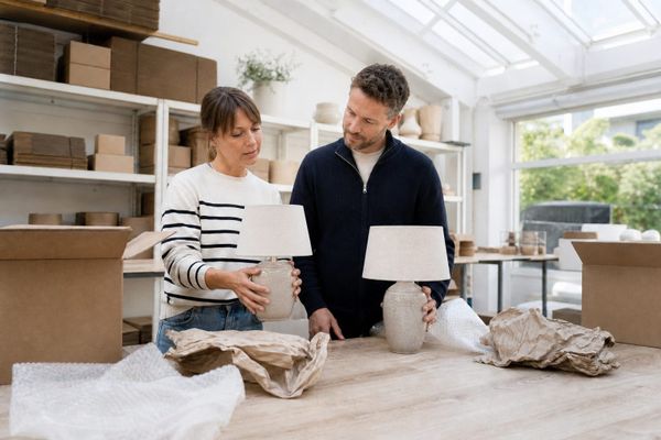 Ecommerce team comparing two intact ceramic table lamps at a bright dispatch bench