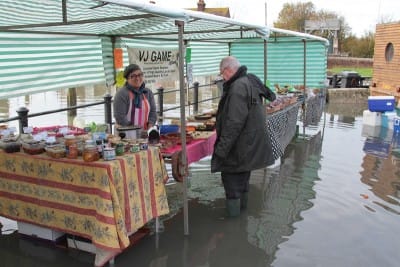 Editor Charles Harkness, suitably booted, consults Kristin from "Gorge on Gorgeous" while V.J.Game rescues boxes from the waves.