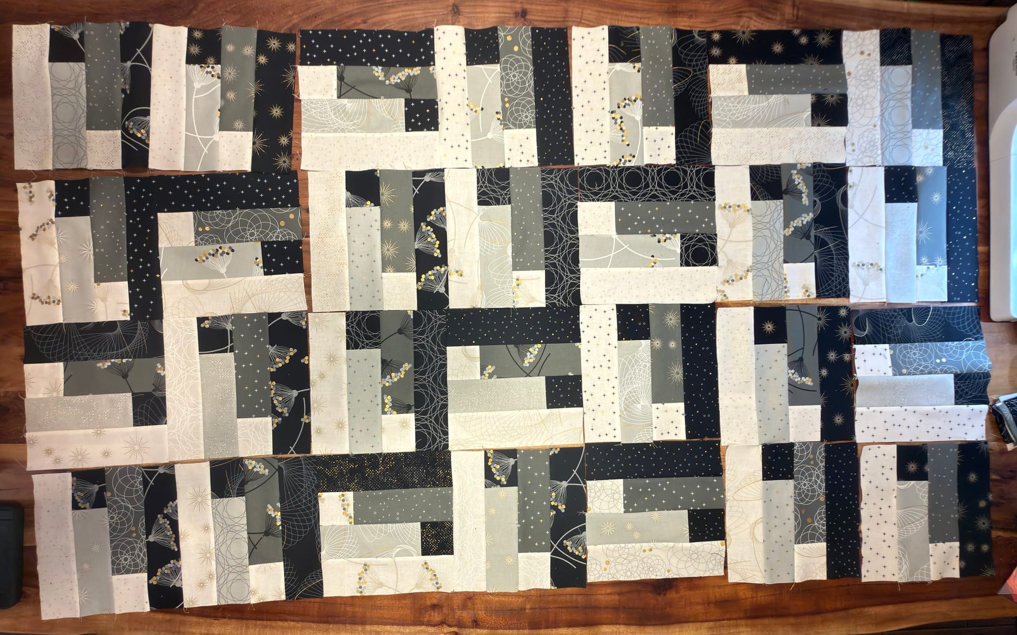 7 columns and 4 rows of the jelly roll quilt block that shows the zig-zag stiars that are almost woven. many blocks have separations since they are just laid next to each other on a wooden table and not all sewn together.