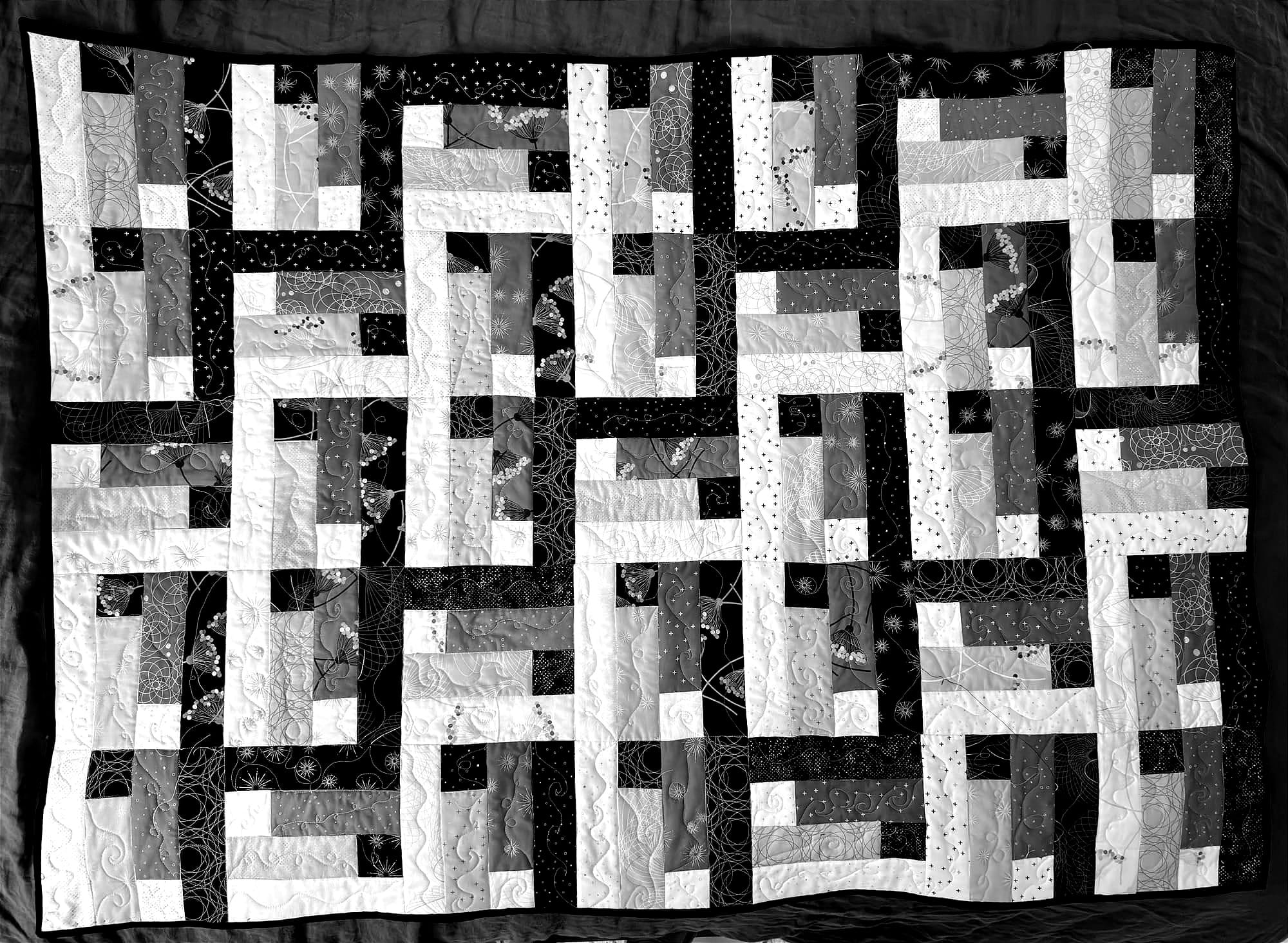 black and white of the quilt lying on a bed showing the pattern of woven stairs