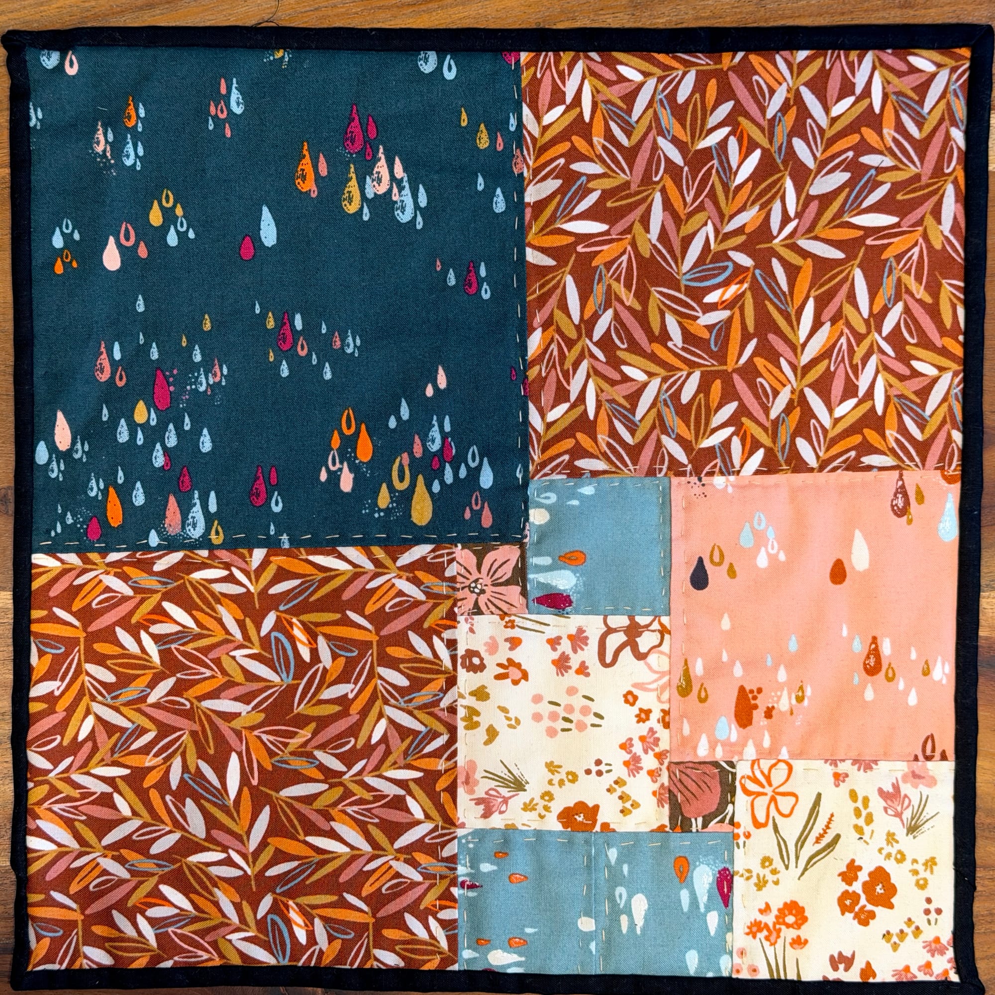 A 13x13 quilt with 11 pieces made of floral and autumn fabric.