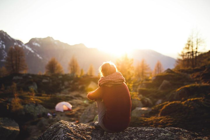 woman looking over her campsite at dawn in the mountains