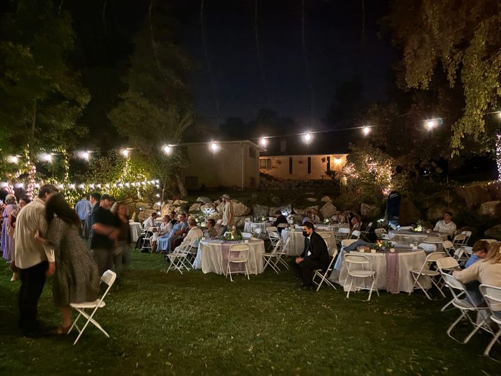 An outdoor wedding with guests dancing and visiting under the lights