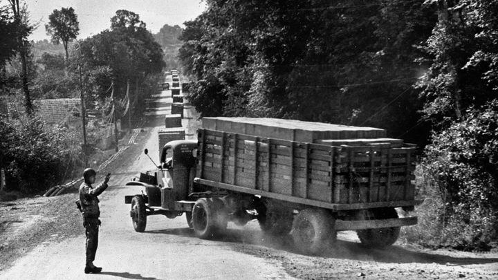 A WWII army truck, loaded with supplies, turns a corner as part of the convoy