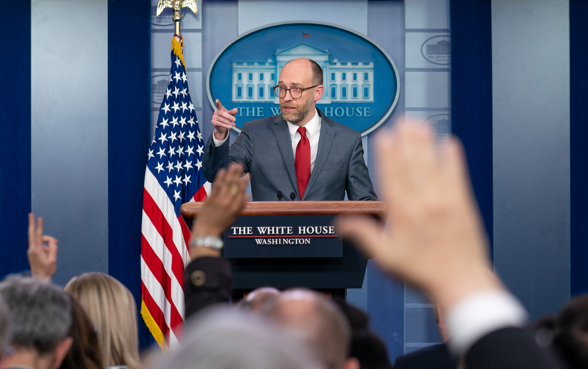 OMB Director Russell Vought at the White House press podium with raised hands in the foregroun
