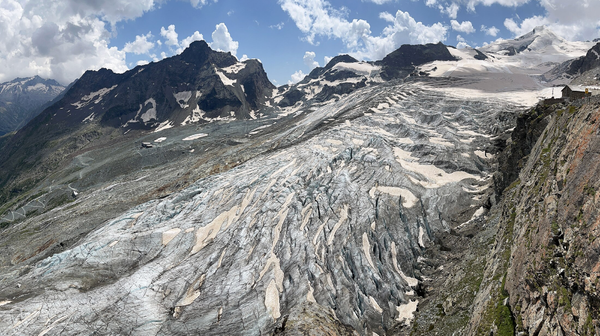 A grayish, grubby glacier surrounding by rock and mountains