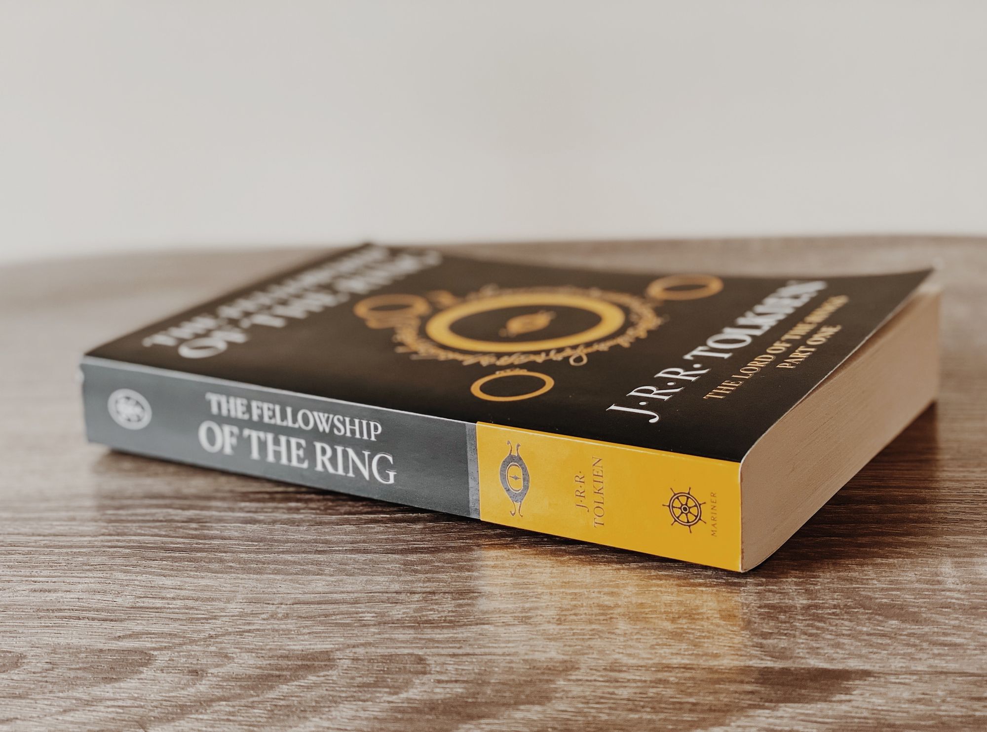 A picture of the book "The Fellowship of the Ring" on a wooden surface