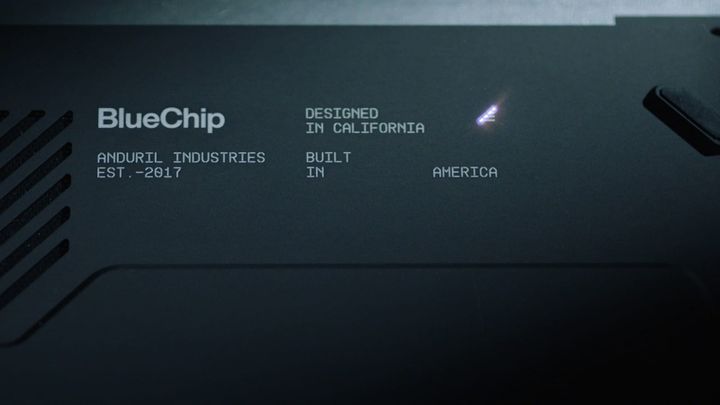 Close-up of the dark casing of Anduril's BlueChip laptop, with vent slots and etched text reading BlueChip, Designed in California, Built in America
