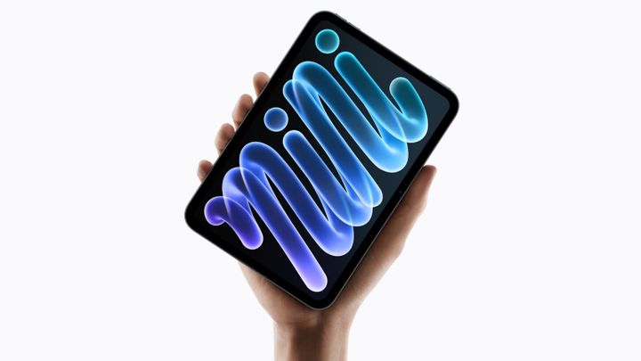 A hand holding up the new iPad mini against a white background, its OLED screen showing a glowing blue and purple swirl