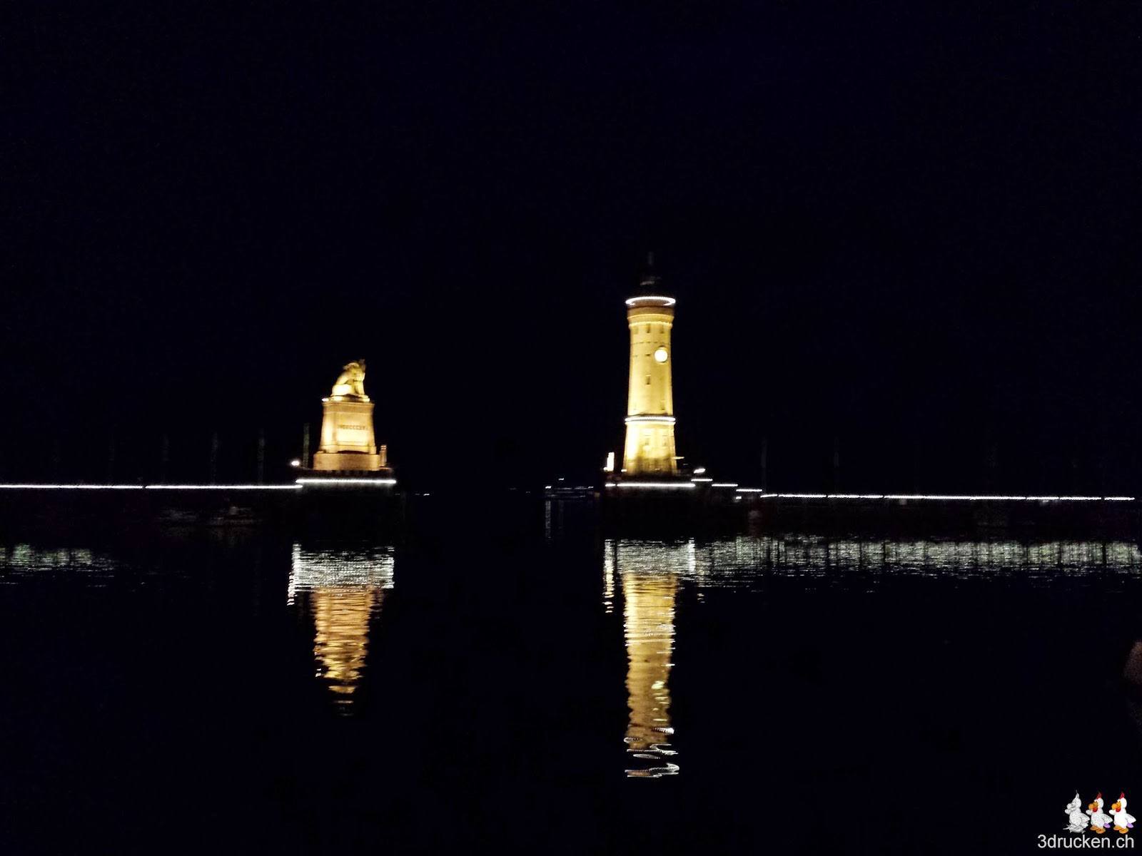 Foto der beleuchteten Hafeneinfahrt von Lindau bei Nacht mit Leuchtturm und Löwen