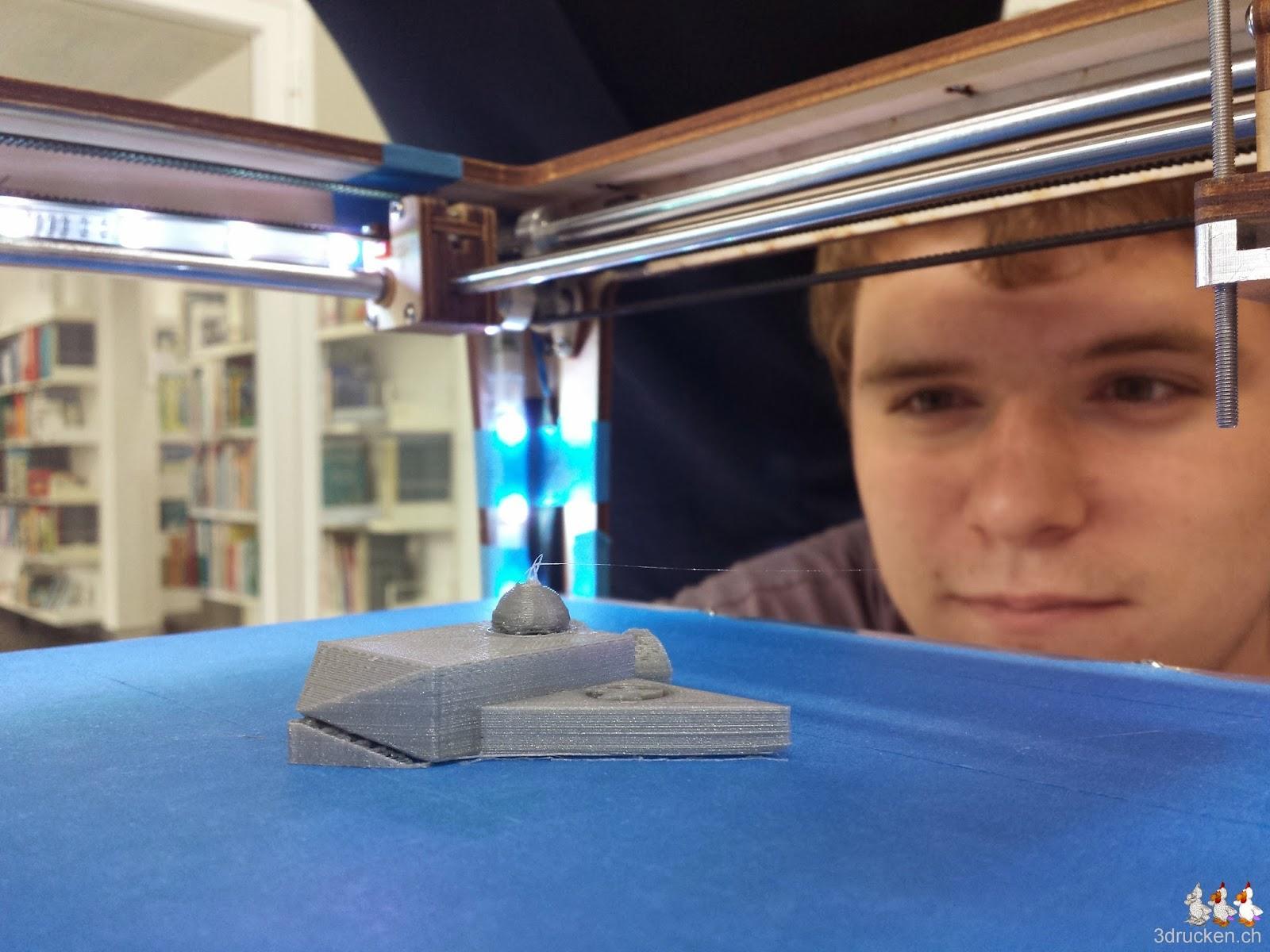 Foto des fertig gedruckten Raumgleiter-Modells auf dem Drucktisch des Ultimaker Original, scharf beobachtet von einem Lernenden