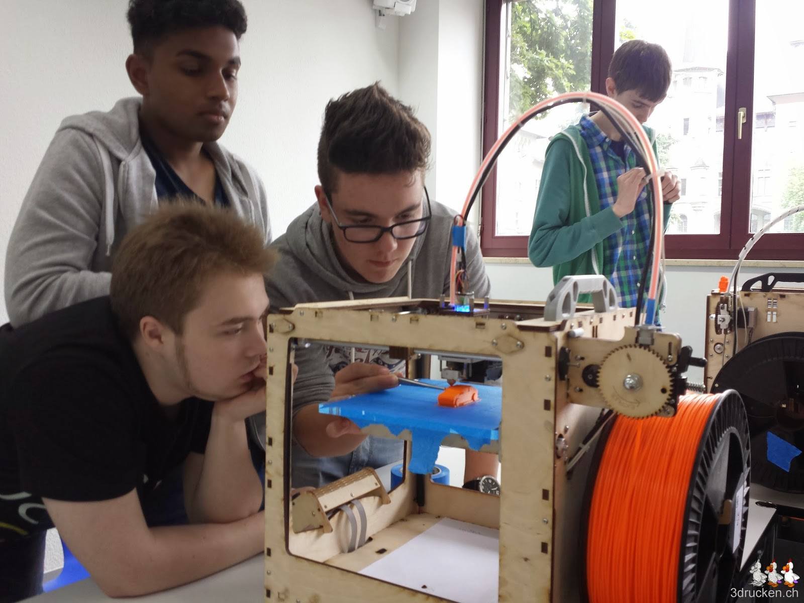 Foto einer Gruppe Lernenden, welche den Ultimaker Original bei der Arbeit beobachtet und versucht beim Drucken zu helfen