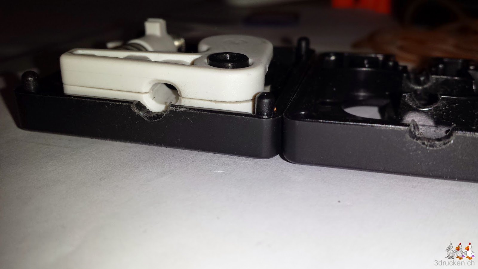 Foto der Unterseite des Feedergehäuses des Ultimaker 2 mit deutlich erkennbarem Abrieb an der Öffnung durch schräg eingezogenes Filament