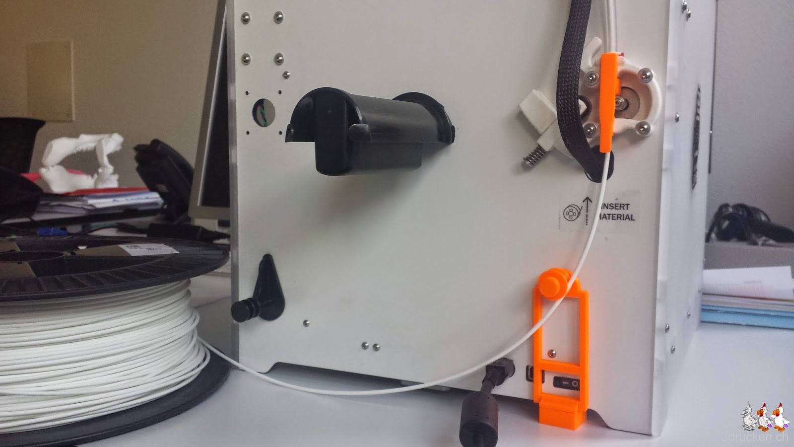 Foto der Rückseite des Ultimaker 2 mit der original Rollenhalterung und dem alternativen Feeder