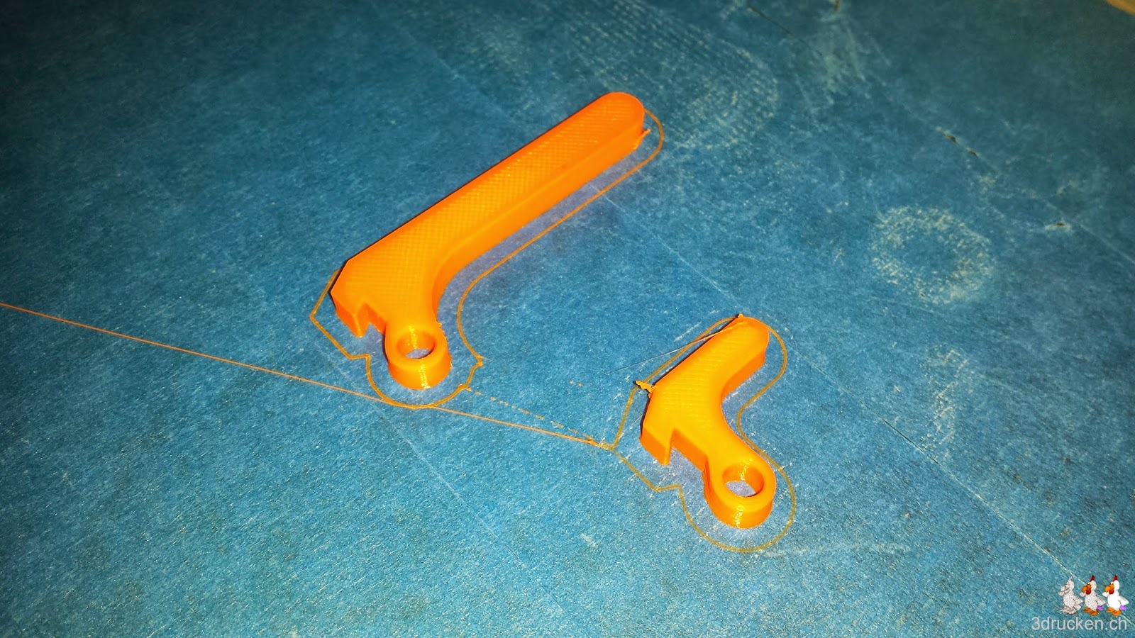 Foto der beiden Versionen des Hebels für den Yet Another Ultimaker 2 Feeder auf dem Drucktisch des Ultimaker Original