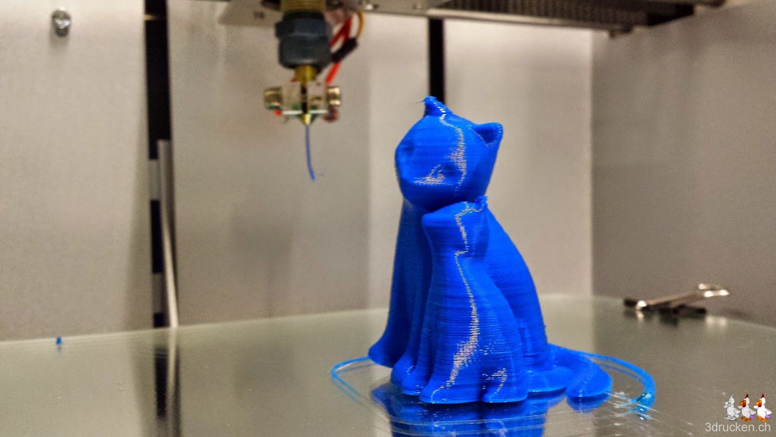 Foto der beiden fertig gedruckten kuschelnden Katzen aus blauem PLA auf dem Drucktisch des NEO