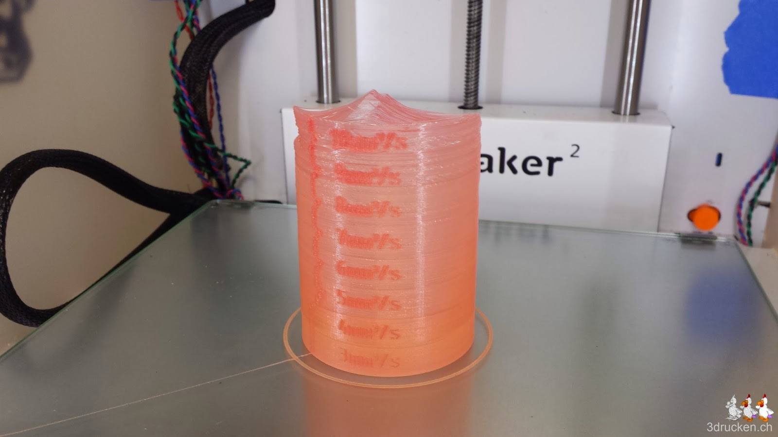 Foto des aus rotem PLA leider nicht perfekt gedruckten Testzylinders auf dem Drucktisch