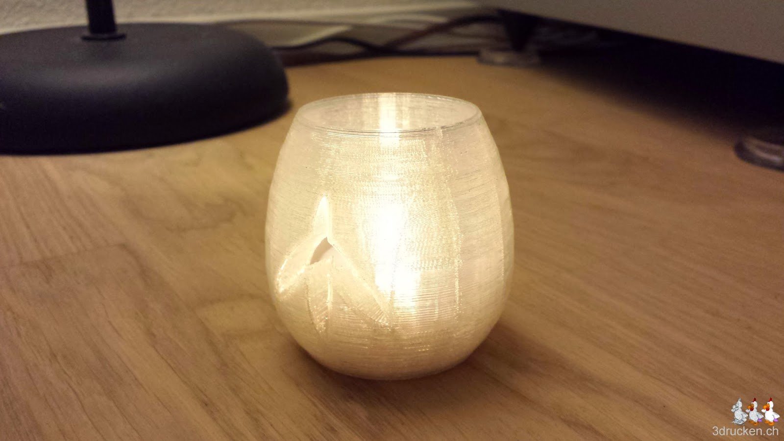 Foto des Teelichts vom Güggel, leuchtend mit elektrischer Kerze drin