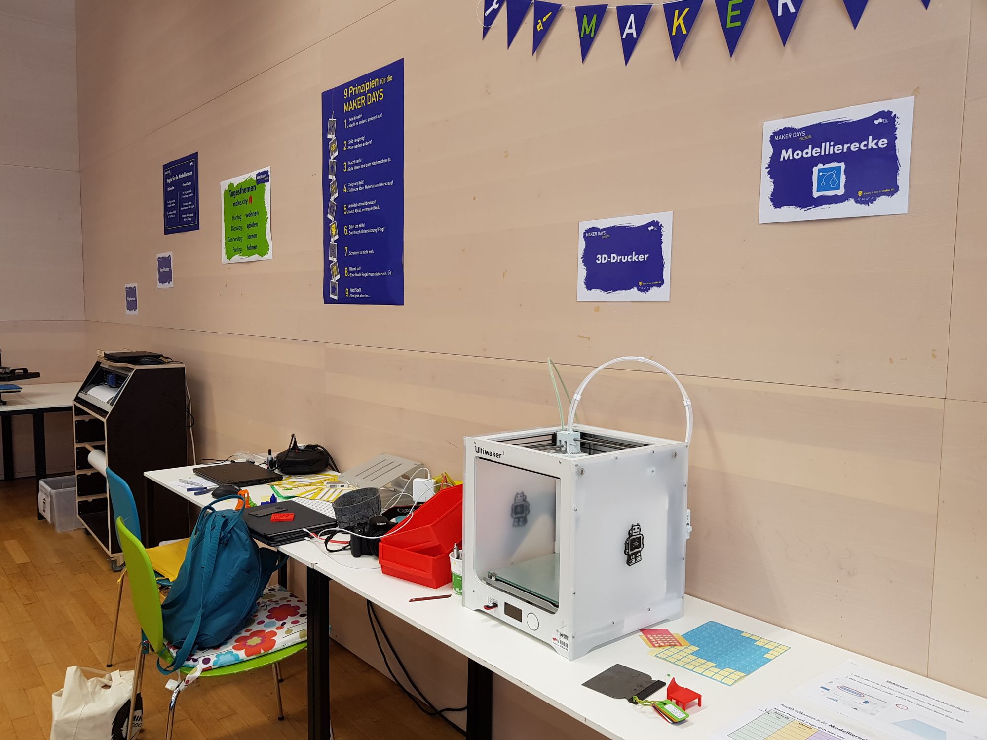 3D-Drucker Ultimaker 3 auf einem Tisch, daneben Zettel zur Beschriftung und Notebooks zur Umwandlung der Modelle.