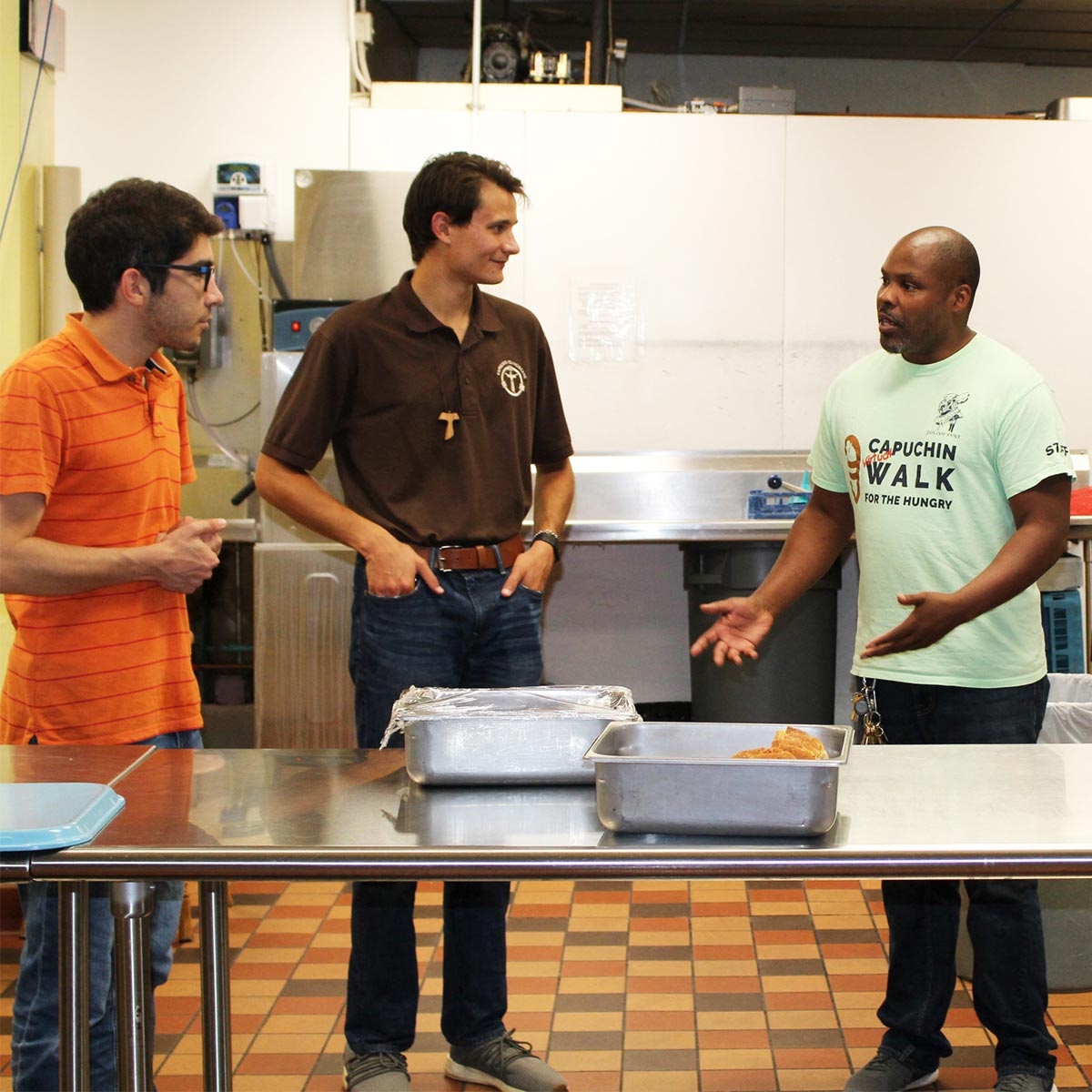 Postulants Álvaro and Andy get a tour of St. Ben’s Community Meal from Kenny Howard.