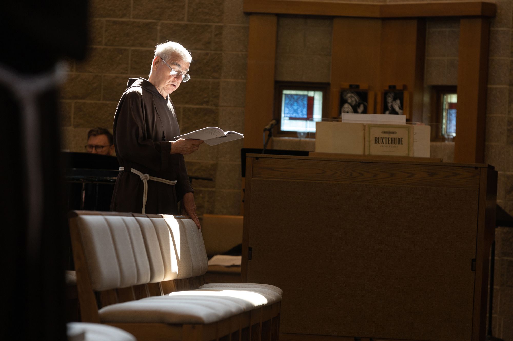 Interior color photo of Friar Tom Zelinski, OFM Cap. leads song during prayer in the St. Xavier University Chapel during the triennial chapter.