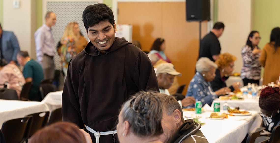 Br. Alwin talks with parishioners during a meal at the St. Francis Capuchin Center.
