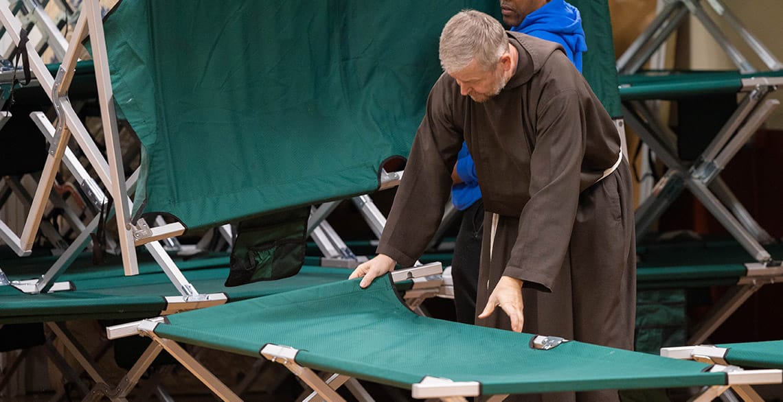 CCS Ministry Director Br. Henryk Cisowski, OFM Cap. sets up a cot at the St. Ben's Warming Center.